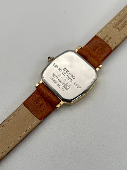 Caseback view of Seiko Exceline vintage women's watch with details engraved, attached to a tan leather strap.