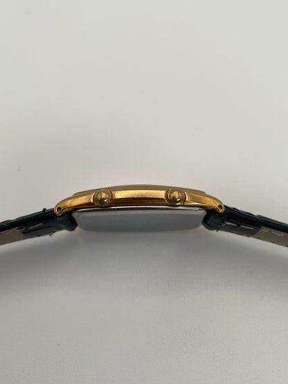 Side crown view of Seiko Noie Dual Time watch with dual crowns on the gold-tone rectangular case and black leather strap.