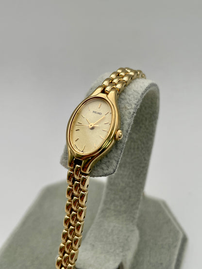 Diagonal view of Seiko Oval 1F21-5A00 showing gold-tone case and champagne dial

