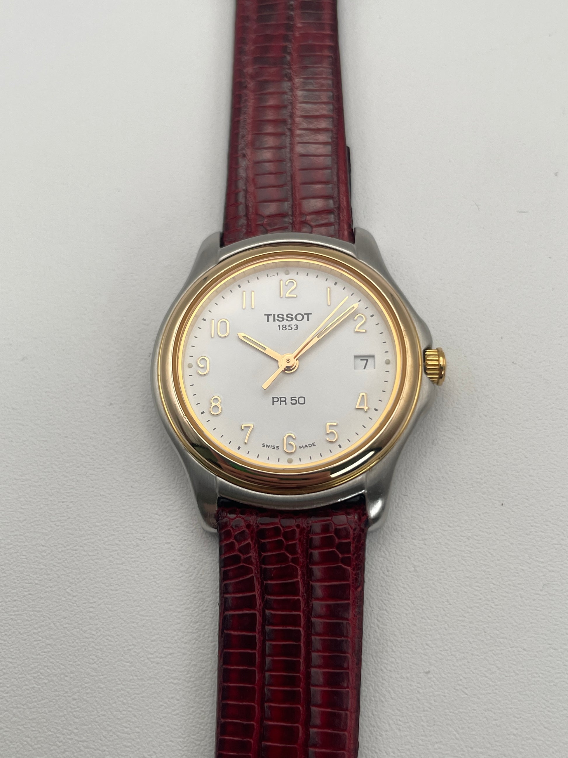 Front view of Tissot PR50 gold and stainless steel vintage watch with red leather strap.