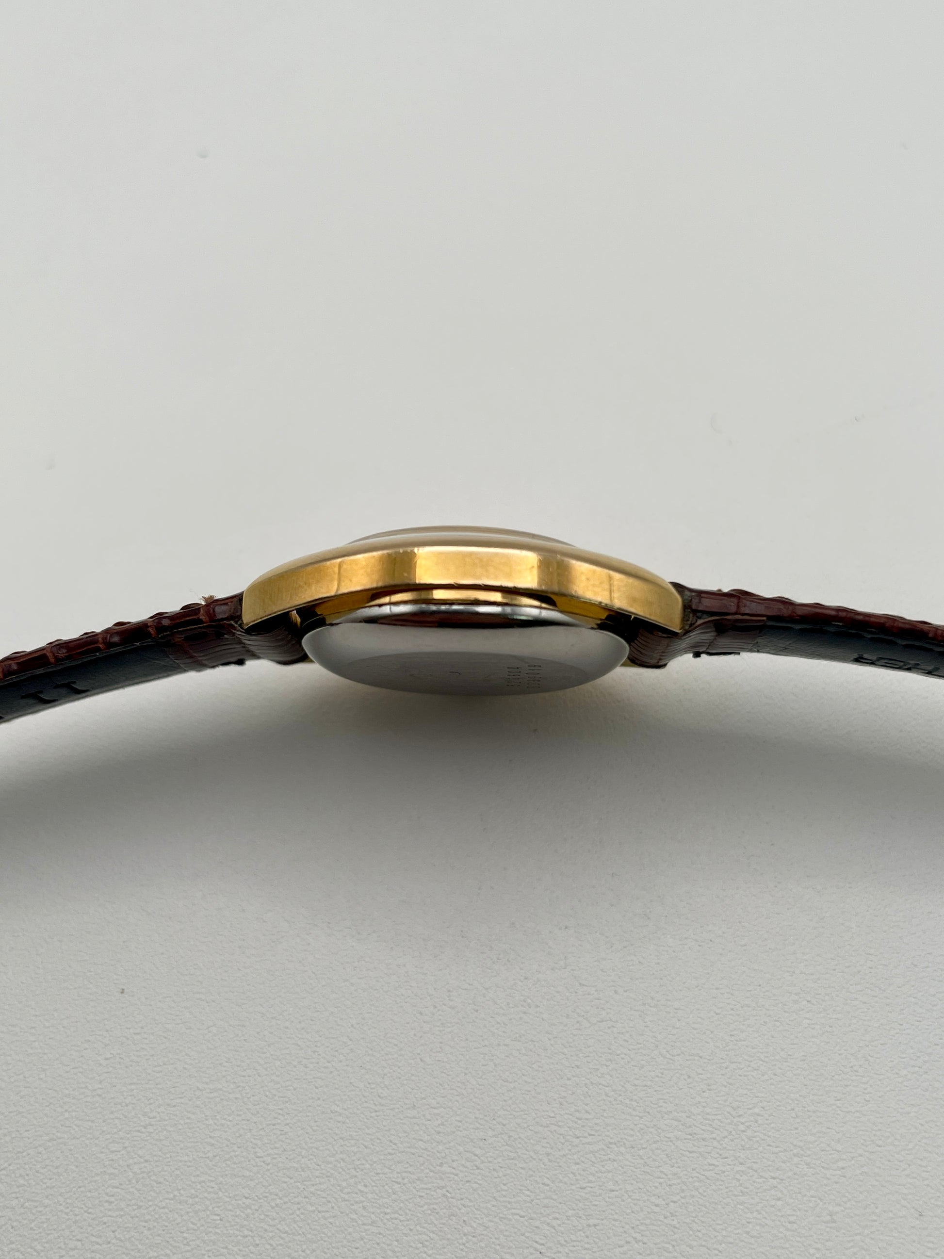 Side profile showing the slim gold case and domed crystal
