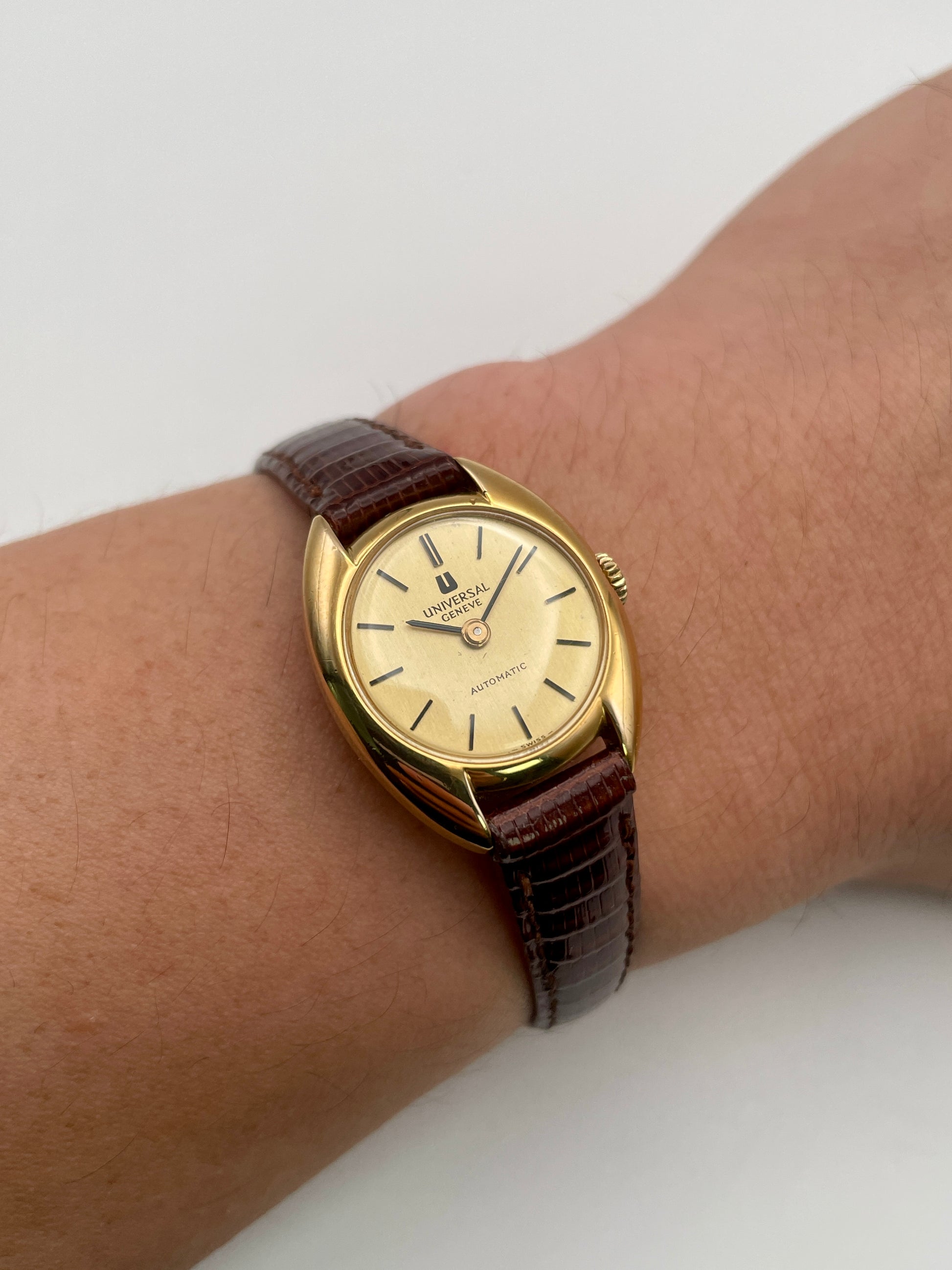Wrist shot showing the Universal Geneve gold watch worn with brown leather strap
