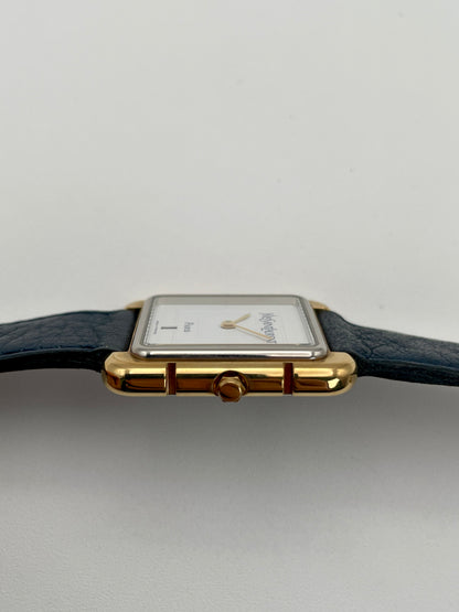 Side view of Yves Saint Laurent 3D Square watch, highlighting the gold crown and case design with blue leather strap.