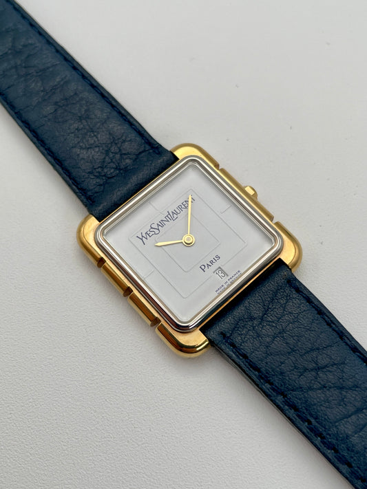 Yves Saint Laurent 3D Square watch with gold case and blue leather strap, white dial, featuring a minimalist design.