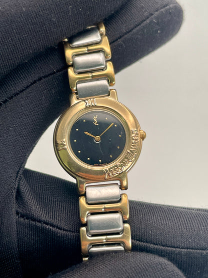 Close-up view of the Yves Saint Laurent Black Pour Femme watch highlighting the dial and engraved branding.