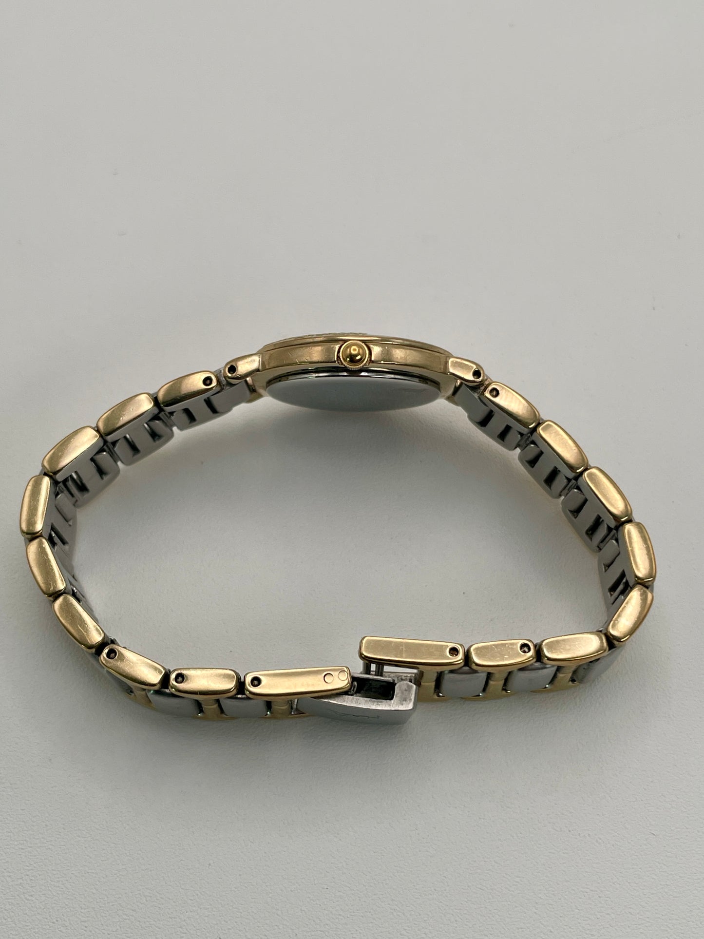 Side view of the YSL watch showing the gold-tone crown and slim case profile.