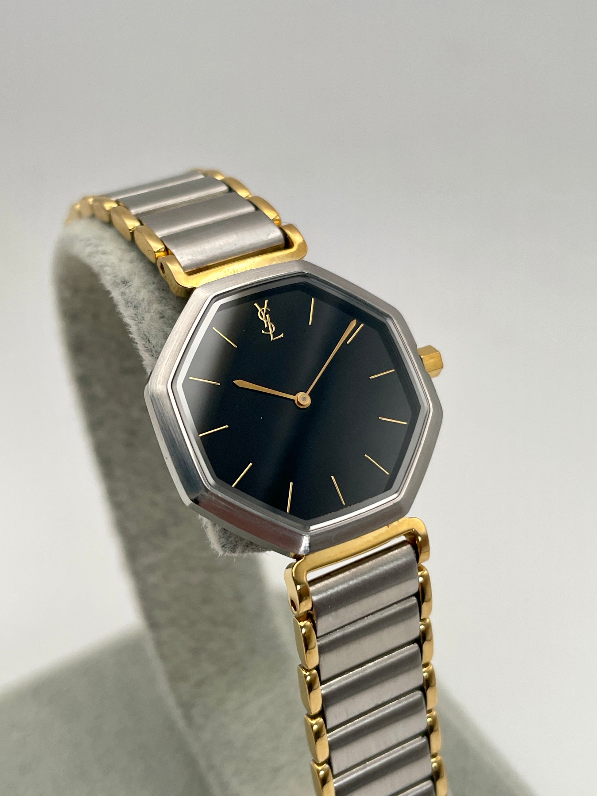 Front view of the Yves Saint Laurent Octagon Vintage Women's Watch featuring a black dial and gold hour markers.