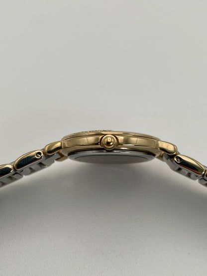 Side crown view of Yves Saint Laurent Pour Femme watch with gold case and two-tone bracelet.