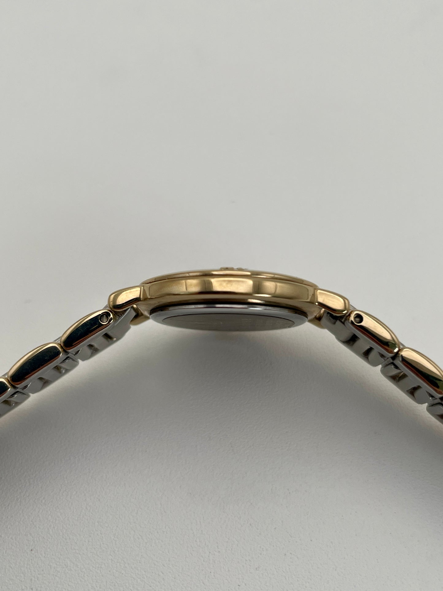 Side view of Yves Saint Laurent Pour Femme watch with gold case and two-tone bracelet.