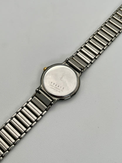 Caseback view of the vintage Yves Saint Laurent two-tone watch, featuring engraved details on the stainless steel back.
