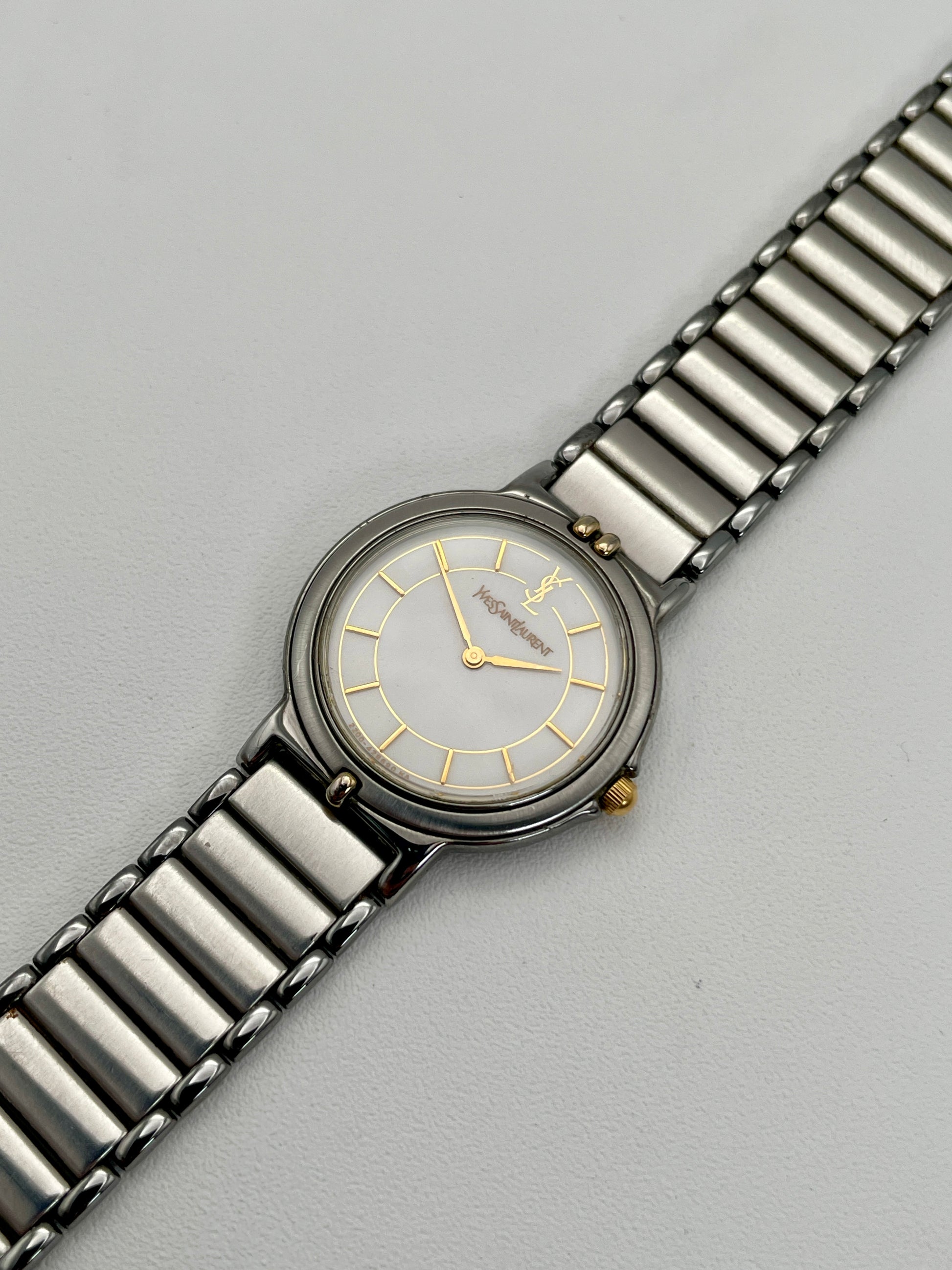 Diagonal view of the vintage Yves Saint Laurent two-tone watch highlighting the stainless steel and gilt bracelet.