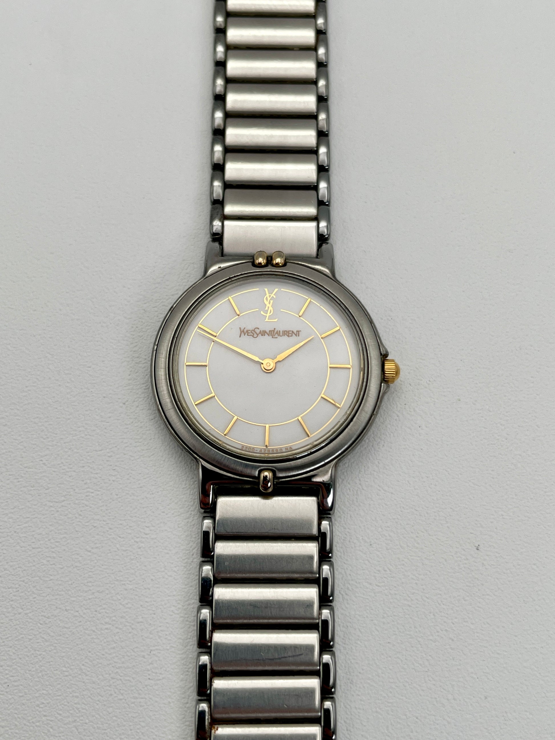 Front view of the vintage Yves Saint Laurent two-tone watch, showcasing the stainless steel and gilt case with a white dial.