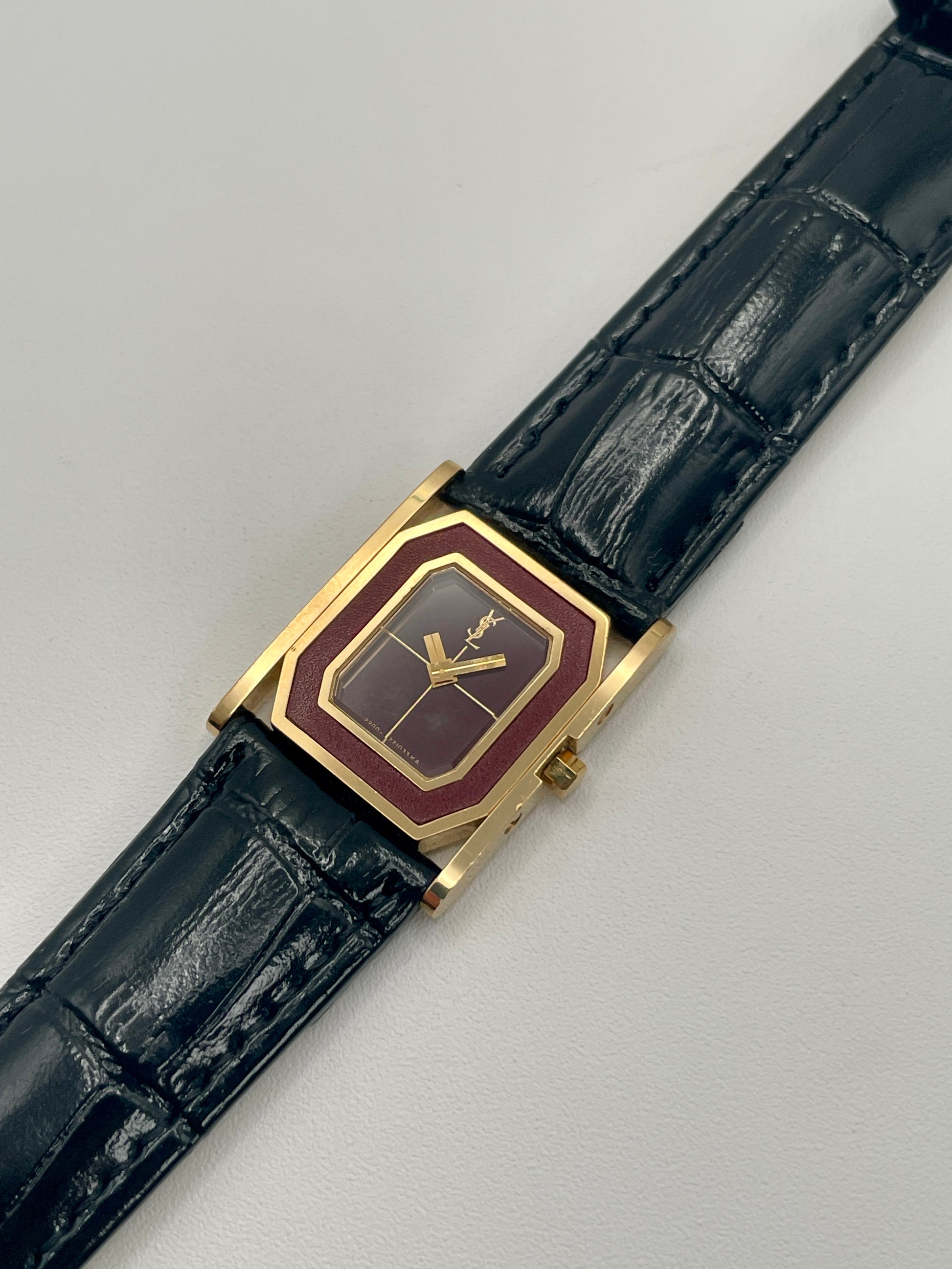 Diagonal right view highlighting the dial, gold bezel, and crown of the YSL vintage watch