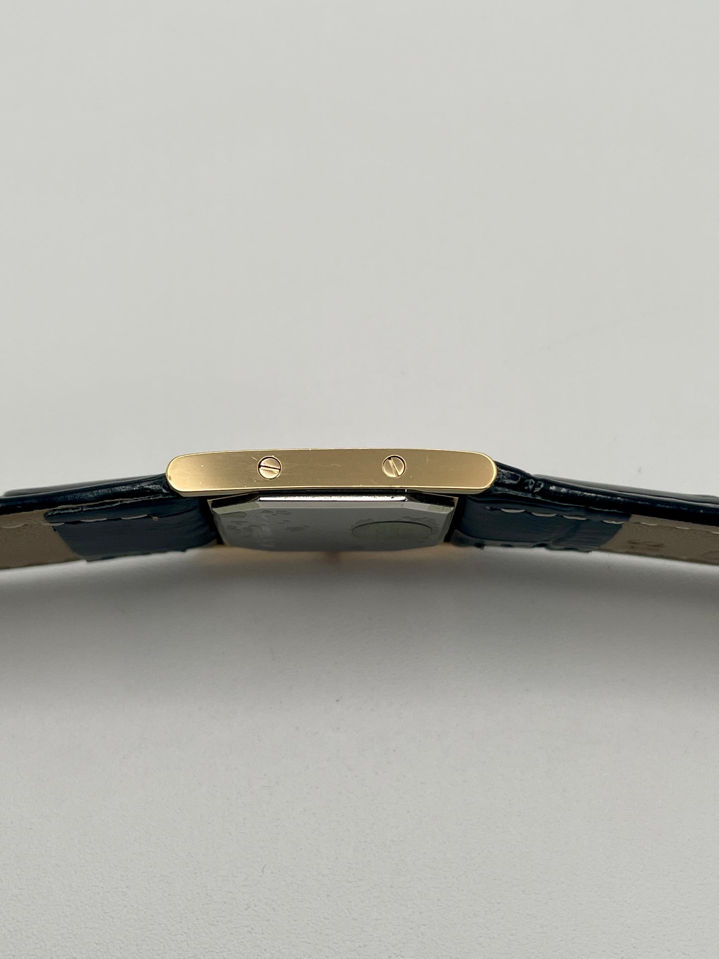 Left side profile of the YSL Tank watch showing flat gold case and screw details