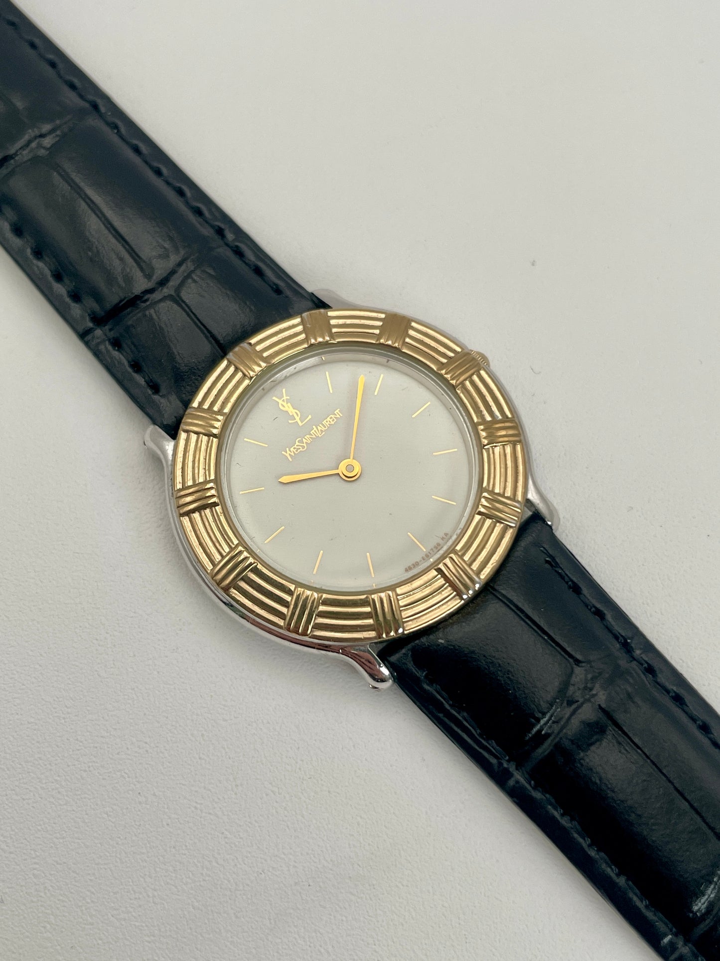 Front view of Yves Saint Laurent vintage watch in two-tone gold and steel with a black leather strap.
