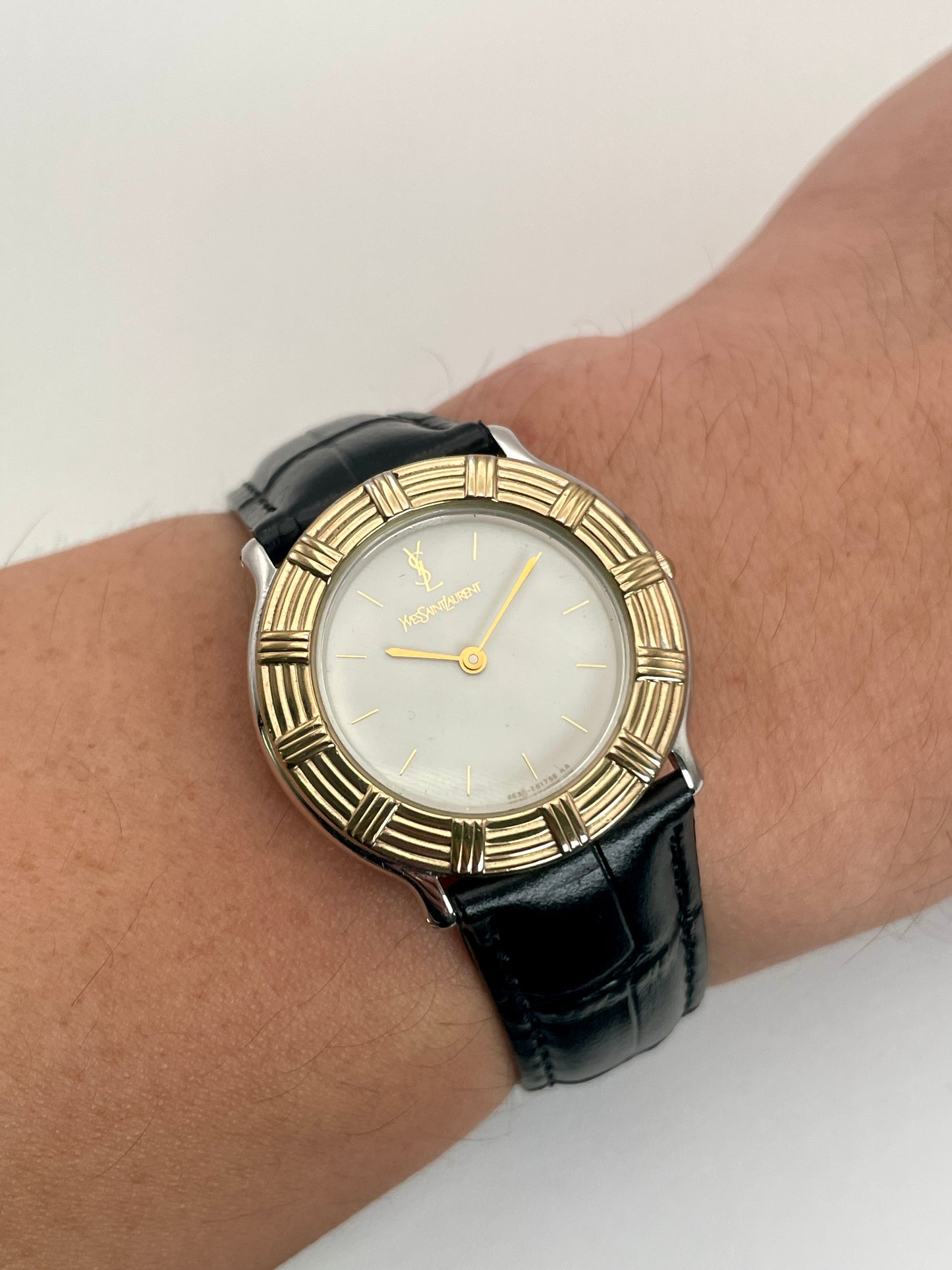 Wrist shot of Yves Saint Laurent vintage watch in two-tone gold and steel with a black leather strap.