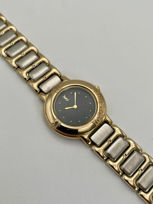 Yves Saint Laurent YSL Pour Femme watch with gold case, black dial, and two-tone bracelet.